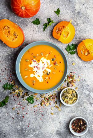 Pumpkin soup with cream and seeds on grey stone background. Top view.の写真素材