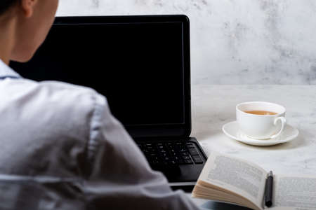 Girl sitting in front of laptop with a blank screen. Online education concept.の写真素材