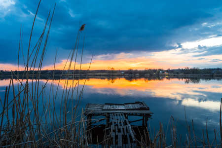Old fishing wooden bridge on the lake at sunsetの写真素材
