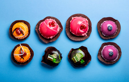 Assorted mousse cakes on blue background top view