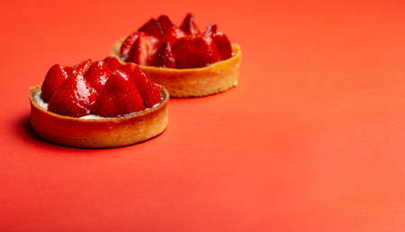 Strawberry tarts with custard on red background copy space close-upの写真素材