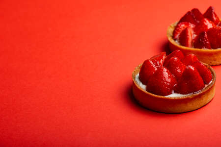 Strawberry tarts with custard on red backgroundの写真素材