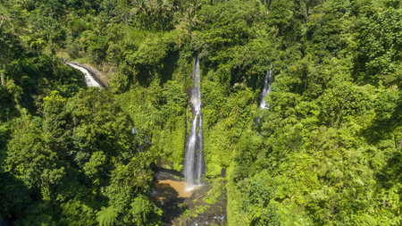 Waterfall with rainbow in green tropical forest on Bali aerial viewの写真素材