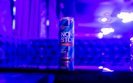 KYIV, UKRAINE - JULY 25, 2023: Can Non Stop energy drink on a glass table in a nightclub background.のeditorial素材