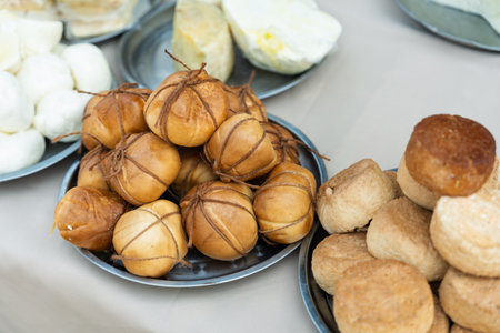 Showcase of delicious farm cheeses from fresh white to aged and smoked for sale at an outdoor fairの写真素材