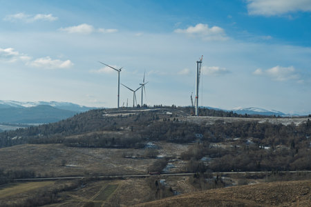 The construction of a wind turbine farm on a scenic mountain landscapeの写真素材