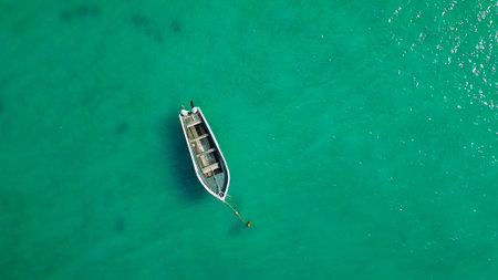 Lonely fishing boat floating above clear teal water overhead composition minimal travel background...