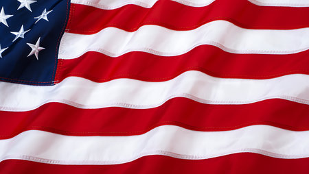 A detailed close-up shot of a waving American flag. The image focuses on the texture and folds of the fabric, showcasing the red and white stripes and the blue canton with white stars.  The colors are vibrant and the texture appears smooth with subtle ripples and waves in the fabric. The focus is sharp, highlighting the fine details of the stitching between the stripes. The overall mood is one of patriotism and national pride.の写真素材