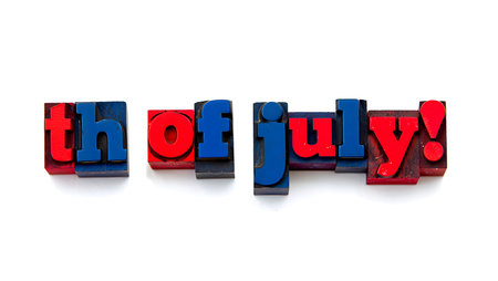Close-up shot of individual letterpress blocks spelling out "th of July!"  The letters are primarily red and blue, set against a stark white background. The blocks appear aged and show signs of wear, giving a vintage feel. The composition is simple and direct, with the words arranged in a linear fashion. The color palette is limited to red, blue, and the white background, creating a strong visual contrast. The overall mood is celebratory and patriotic, suggestive of the Fourth of July holiday.の写真素材