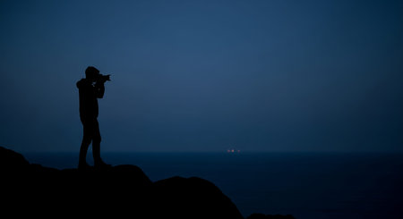 Silhouette of a photographer with a camera on a cliff.の写真素材