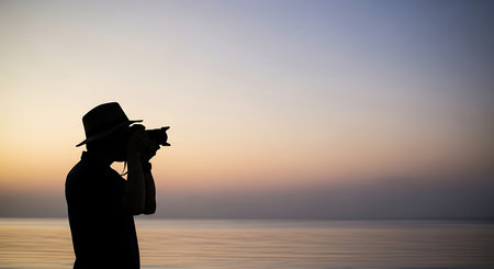 Silhouette of a photographer with a camera on the beach at sunsetの写真素材