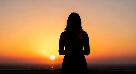 Silhouette of a woman on the background of the setting sunの写真素材