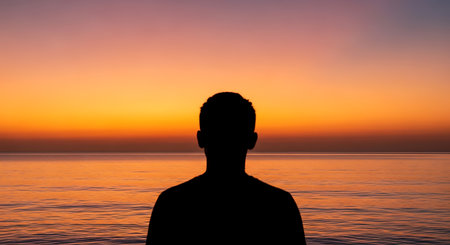 Silhouette of a man at sunset on the sea background.の写真素材