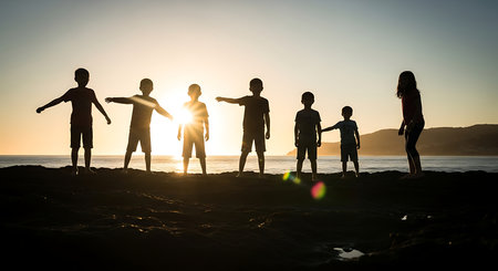 Silhouette of a group of children standing on the beach at sunsetの写真素材