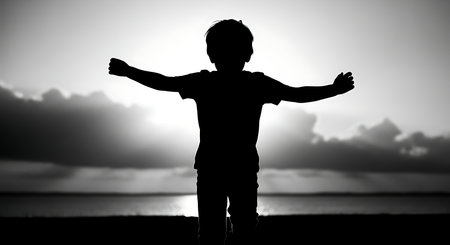 Silhouette of a boy standing on the beach at sunset.の写真素材