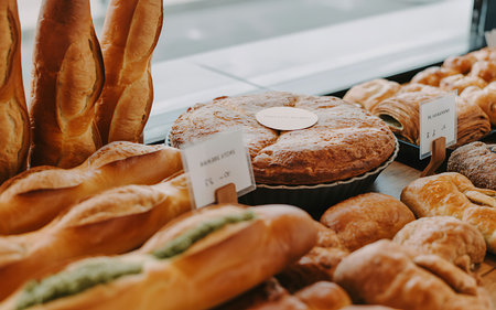 A closeup captures a mouthwatering display of freshly baked goods at a bakery featuring golden brown baguettes a rustic round loaf and an assortment of delectable pastries bathed in soft window light showcasing the artisanal craftsmanship and inviting aroma of a traditional bake shop perfect for food bloggers and bakery enthusiastsの写真素材