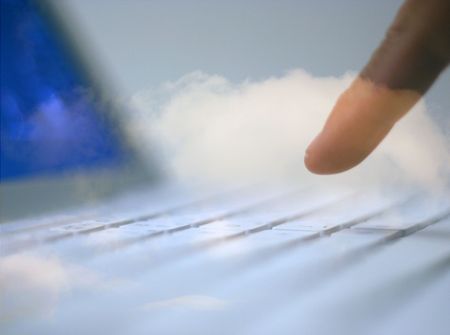 Man using laptop overlaid with cloudy sky.の写真素材