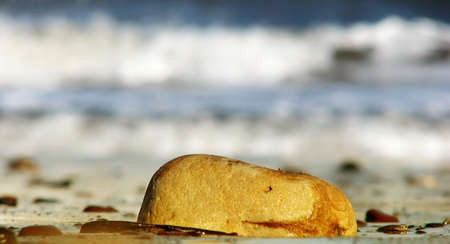 Focused on stone in foreground with out of focus waves in backgroundの写真素材