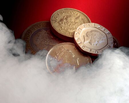 UK coins on red background overlaid with smoke effect.の写真素材