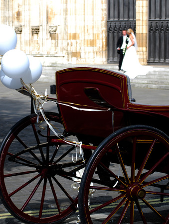 Wedding coach outside of church with bride and groom in background (out of focus).の写真素材