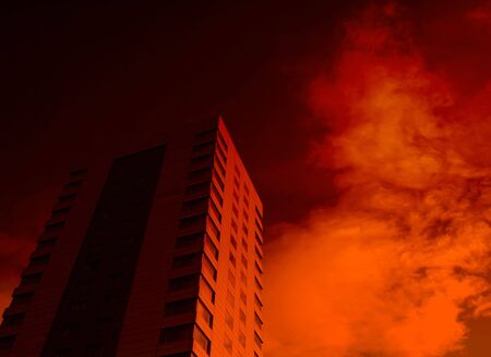 Red lighting effect applied to office building against cloudy sky giving menacing effect.の写真素材