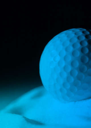 Golf ball in sand with blue lighting effect simulating moonlightの写真素材