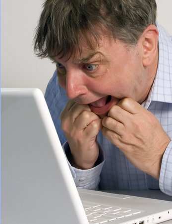 Middle aged man looking in disbelief at laptop screen