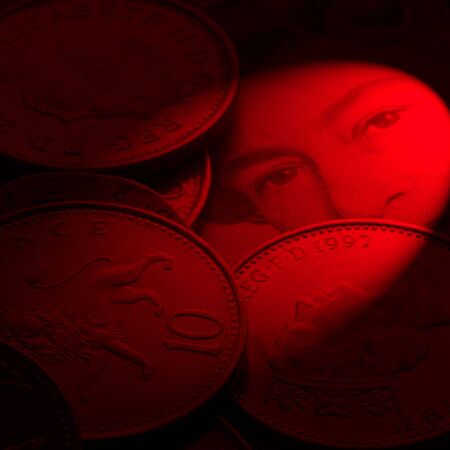 Close-up if British coins resting on bank note. Red lighting for effect.の写真素材