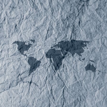 World map overlaid onto blue textured paperの写真素材