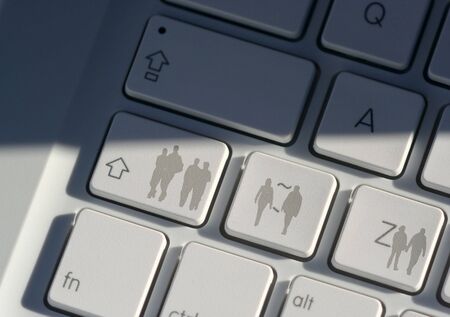 Silhouettes of people overlaid on to laptop keyboardの写真素材