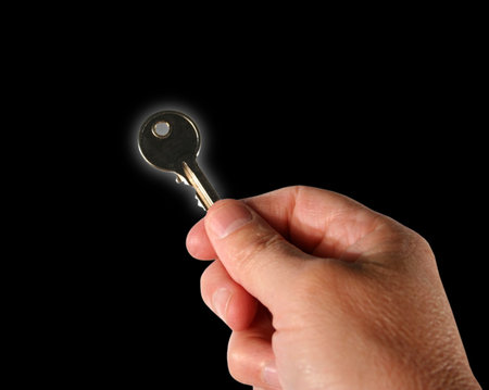 Male hand holding latch key over black. Key with glow effect.