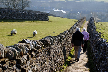 Elderly couple walking along path in Grassington, Yorkshire, UK.