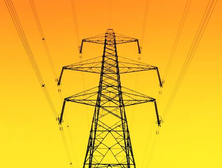 Electricity pylon and cables over yellow/orange grad backgroundの写真素材