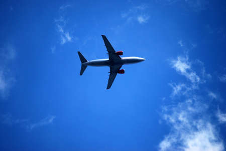 Aircraft flying in cloudy blue sky on sunny dayの写真素材