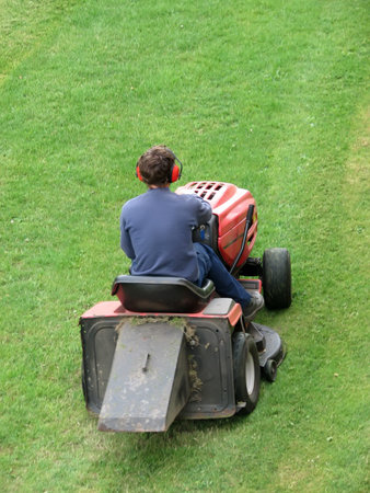 Male cutting grass while riding lawn mover