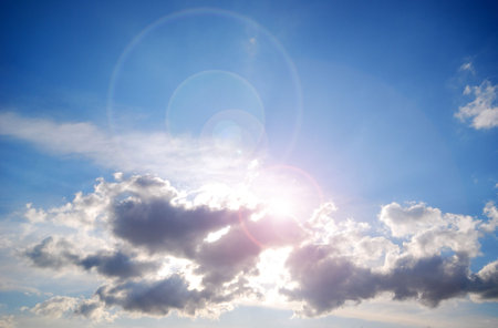 Sun shining behind clouds with lens flare effect