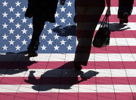 American flag overlaid over silhouetted pedestriansの写真素材