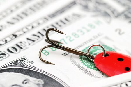 Close-up of fishing hook resting on US dollar noteの写真素材