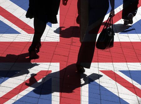 UK flag overlaid over silhouetted pedestrians in city centerの写真素材