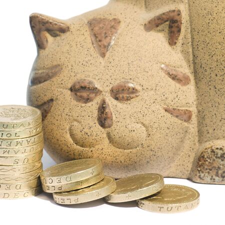 Pile of coins in front of cat shaped piggy bankの写真素材