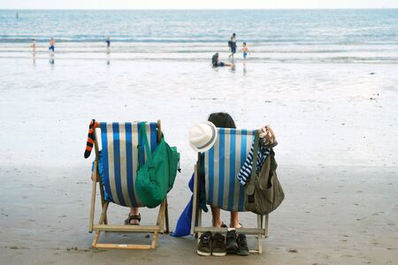 Couple relax in deckchairs on UK beachの写真素材