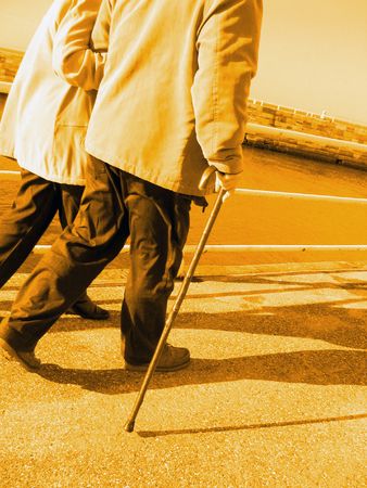 Two seniors walking on pier with yellow lighting effectの写真素材