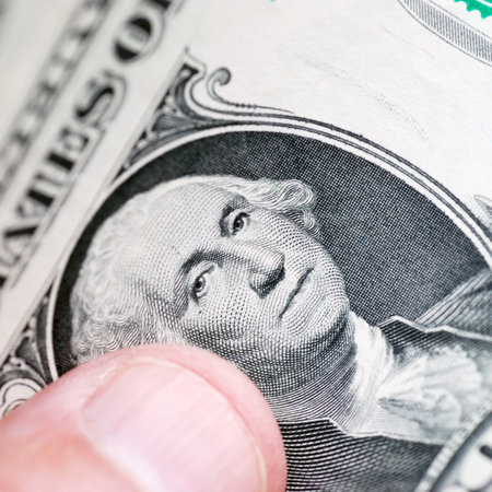Closeup of thumb holding one dollar bills