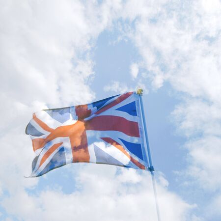 Semi transperant British flag overlaid over cloudy skyの写真素材