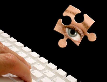 Male fingers using computer keyboard with eye jigsaw pieceの写真素材