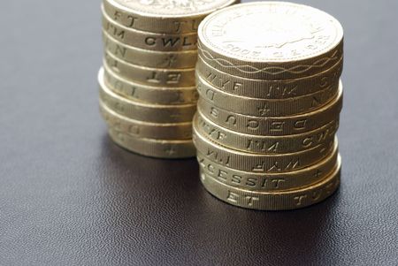 Two stacks of UK Pound coins on textured surfaceの写真素材