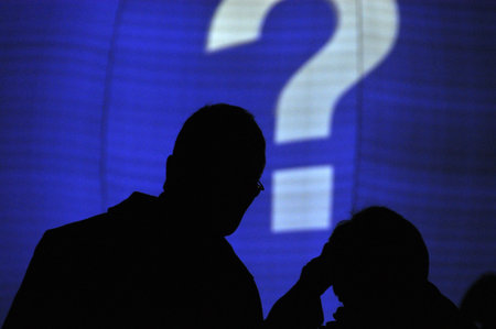 Silhouette of elderly couple looking at screen with question mark