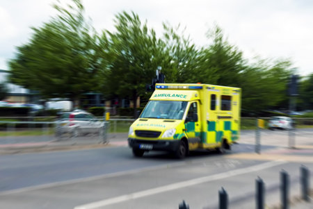 Emergency ambulance races through city street. Zoom blur added for effect.