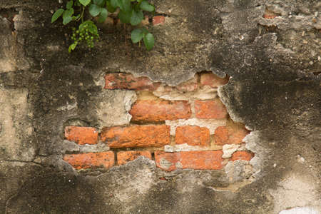 The ancient cement walls constructed of red bricks are cracked, patterned, mottled and dirty over time.の写真素材