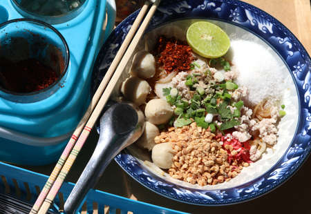 Tom Yum Pork Noodles with Pork Balls - Chilli and Lemon Juice - Cayenne - Peanuts, taken in the afternoon and shaded by sunlight.の写真素材